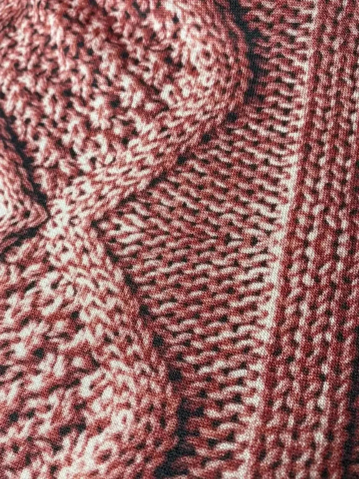 Close-up of pink textured cable knit fabric with rose pattern.