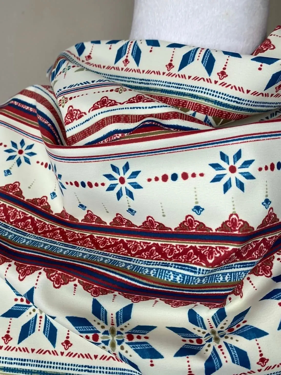 White fabric with red and blue patterns, including snowflakes and stripes.