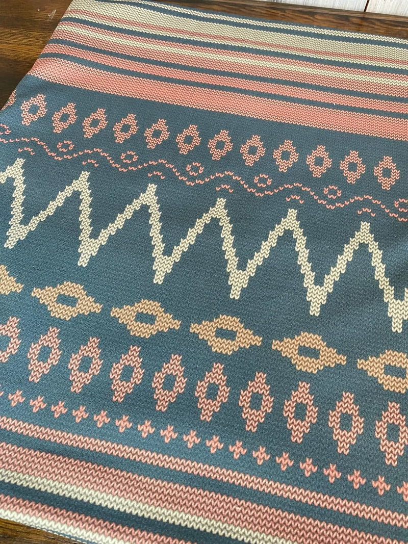Fabric with a blue background and pink, white, and tan geometric patterns.