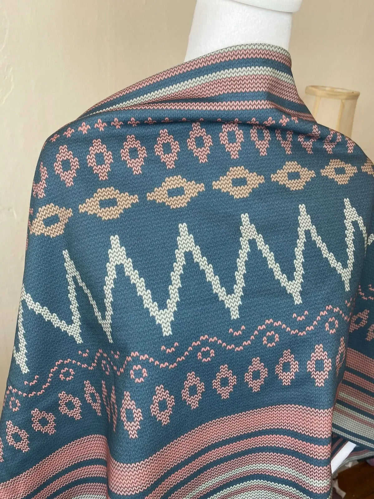 A blue fabric with pink, beige, and white geometric patterns.