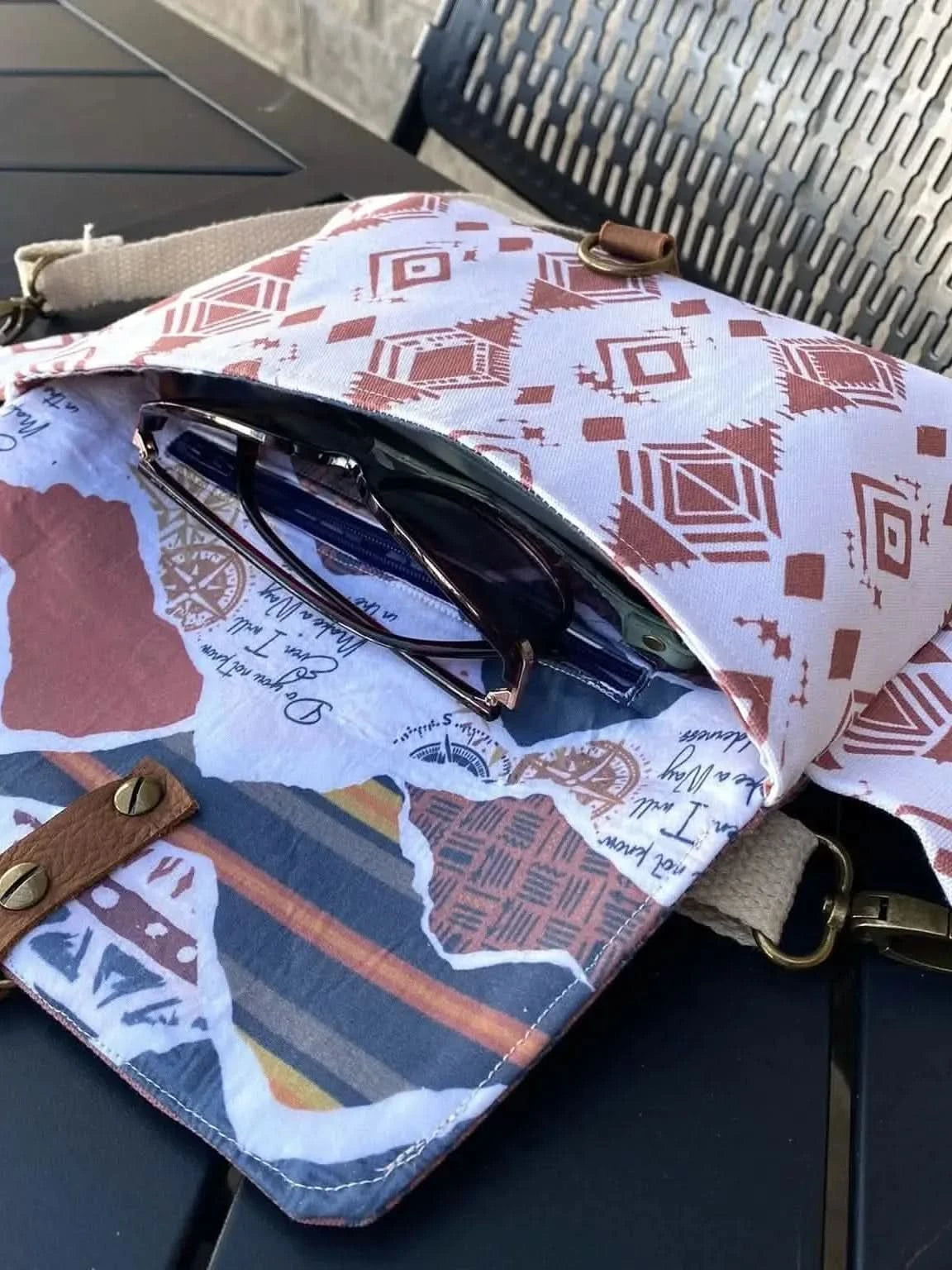 An open fabric bag with a desert flame pattern and a brown leather strap.