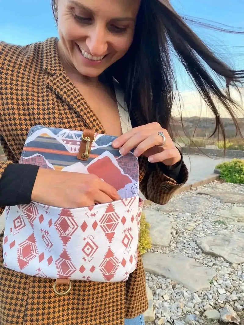 Close-up of a woman holding open a bag made from Desert Flame Southwestern print fabric with geometric red and white patterns.