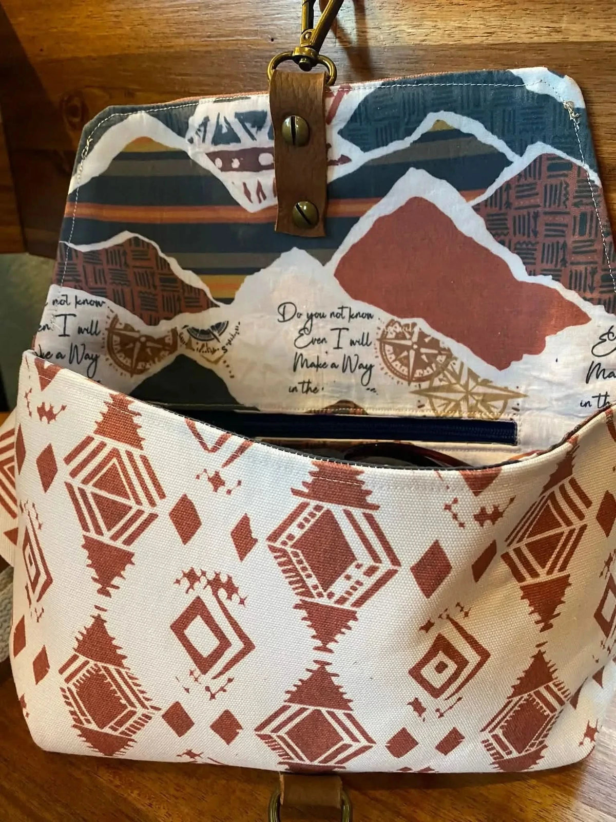 An open fabric bag with a desert-themed pattern and a quote on the inner flap.