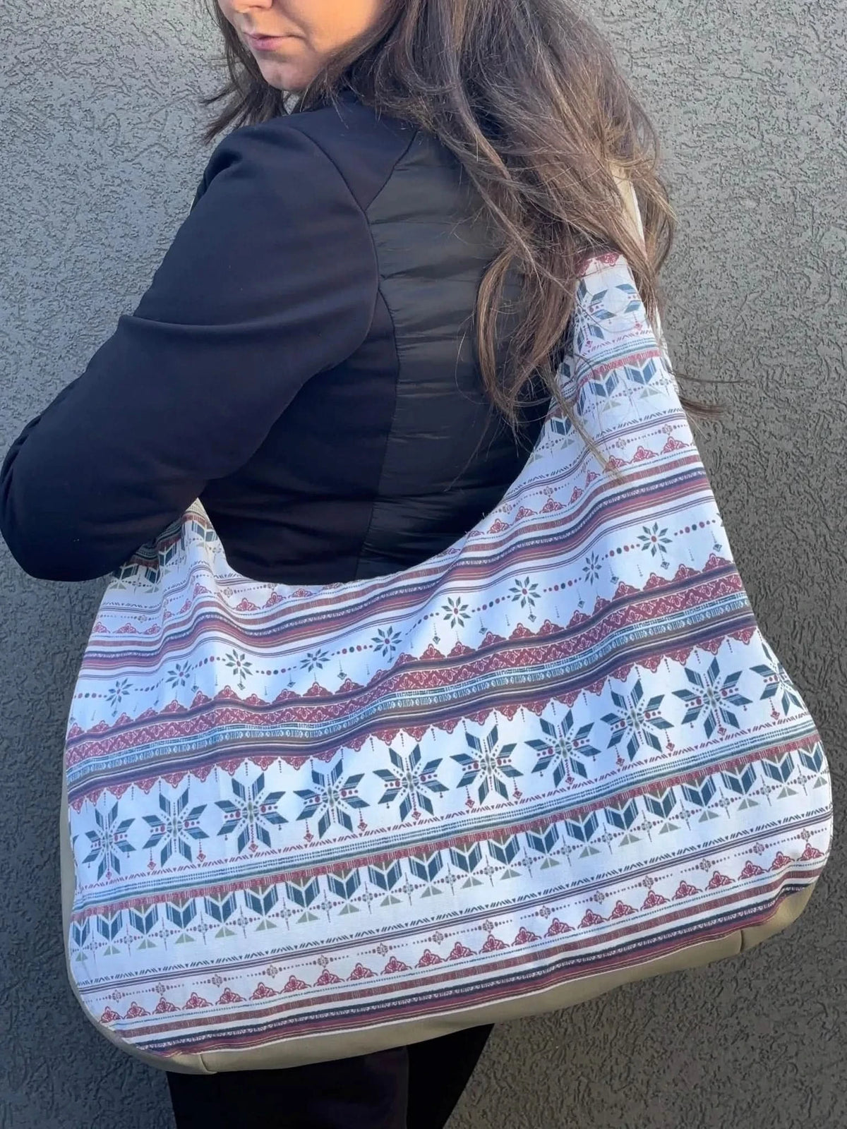 A woman carries a large patterned bag with a winter-themed design.