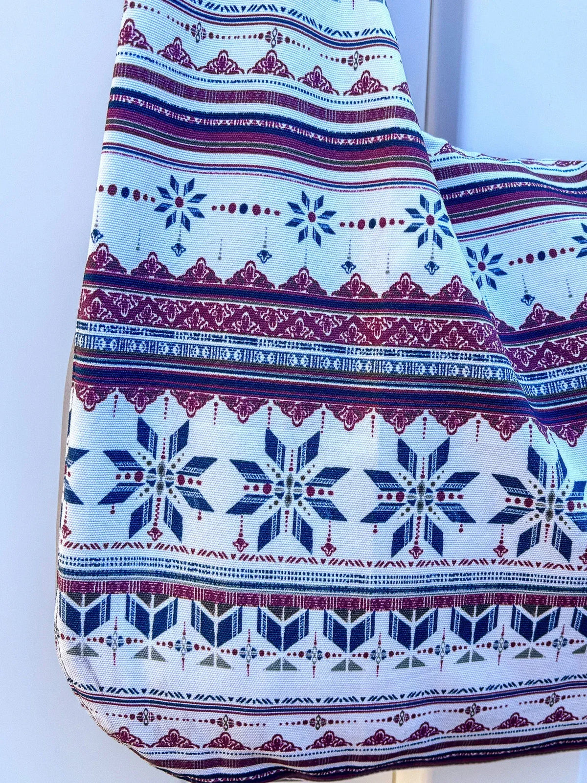 Fabric with a blue, white, and maroon geometric and snowflake pattern.