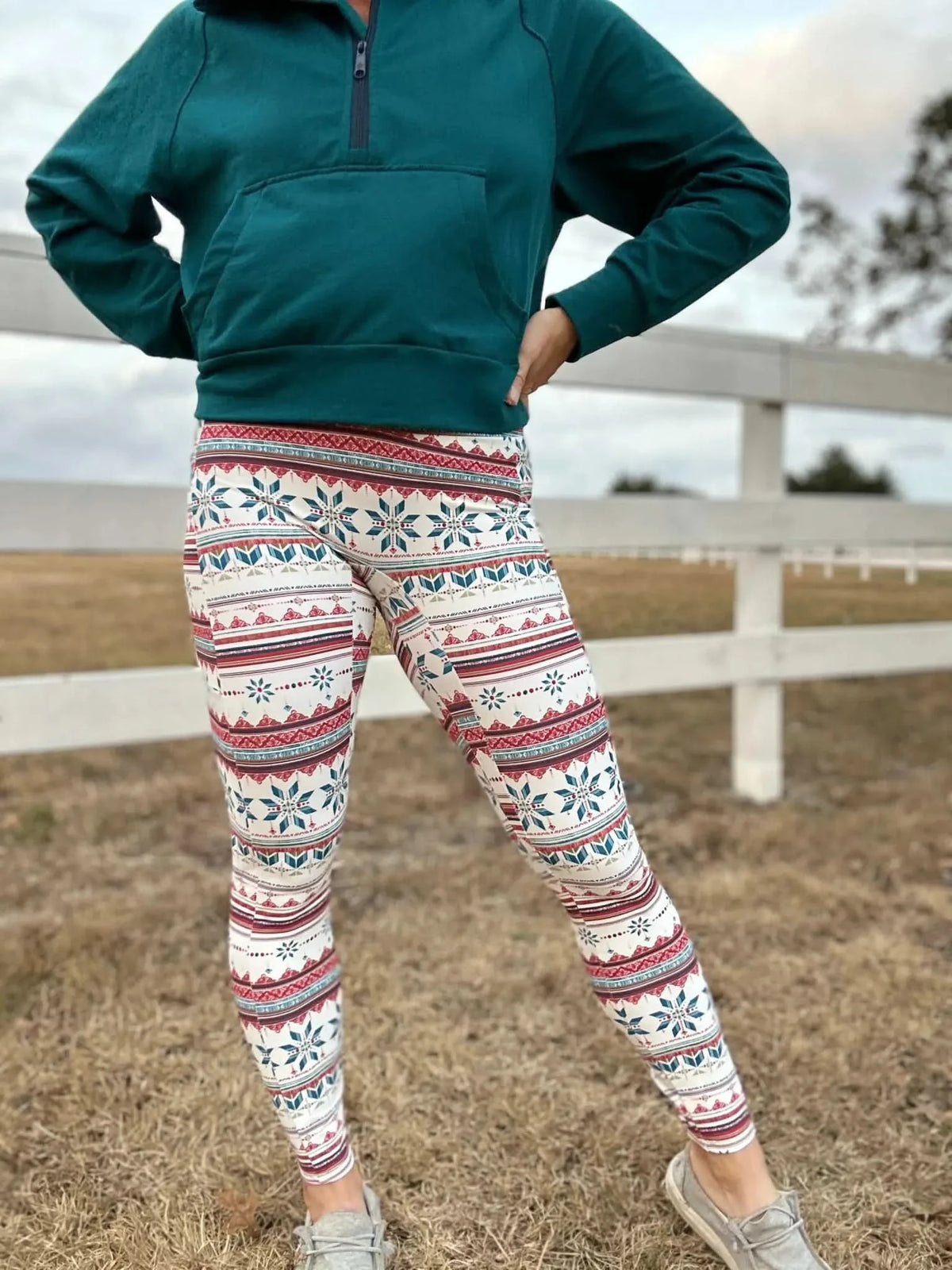 A person wears a teal hoodie and white leggings with a red and blue snowflake pattern.