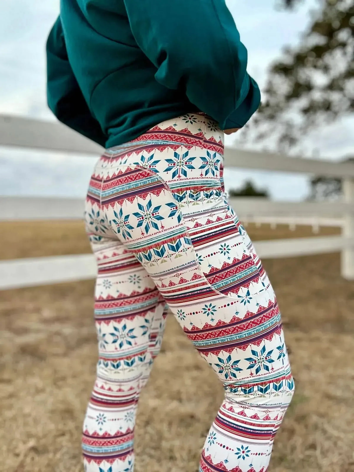 A person from the waist down wearing white leggings with a red and blue snowflake pattern.