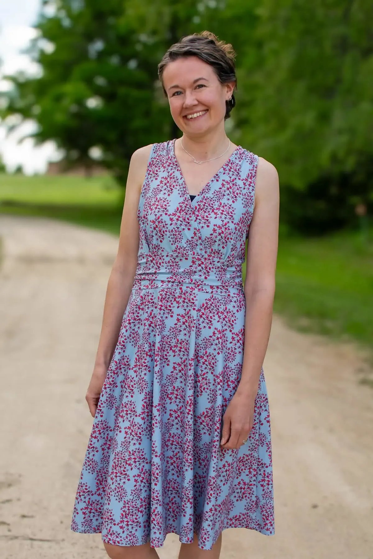 Woman in a light blue dress with small red floral patterns.