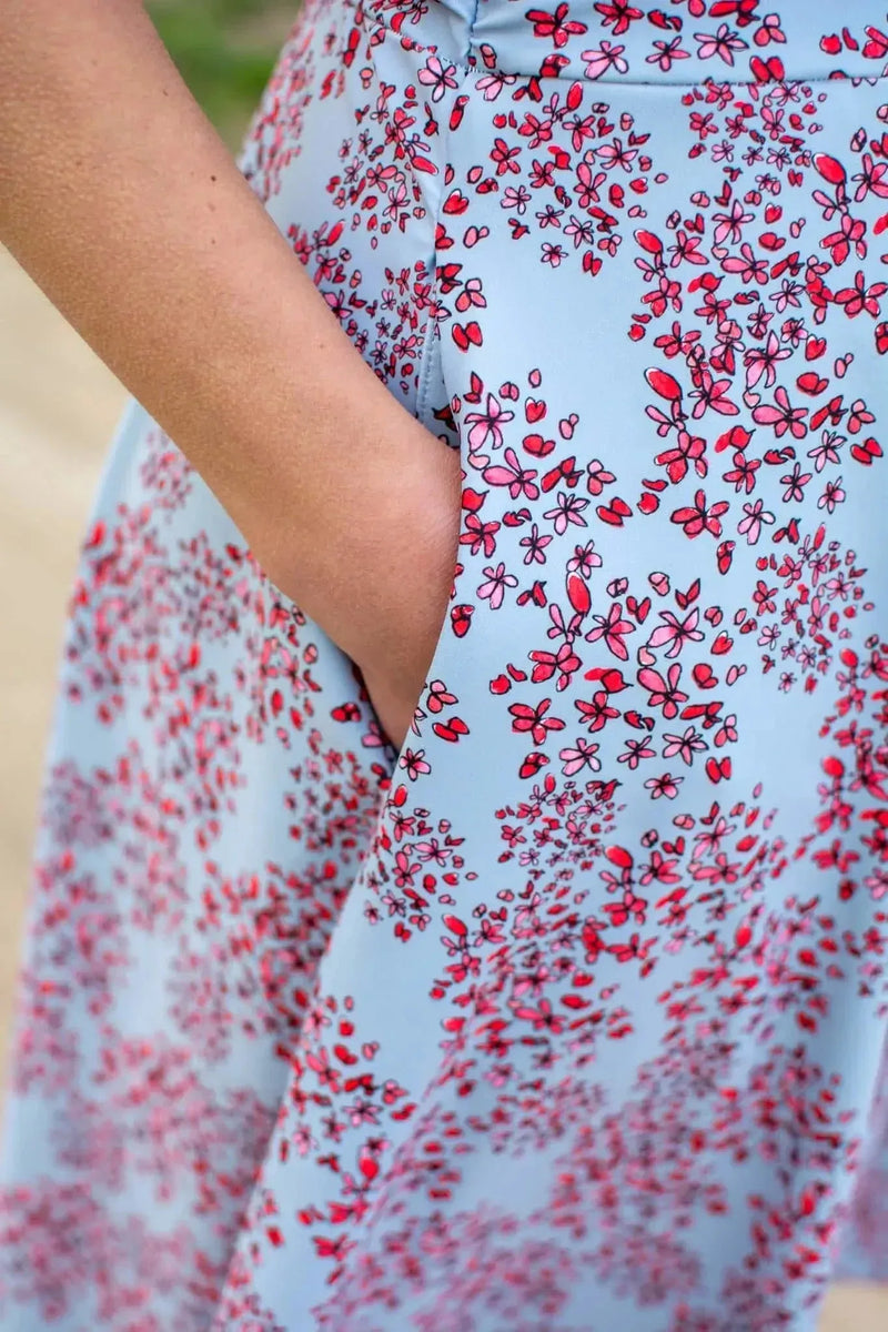 Light blue fabric with red floral pattern, featuring a hand in the pocket.