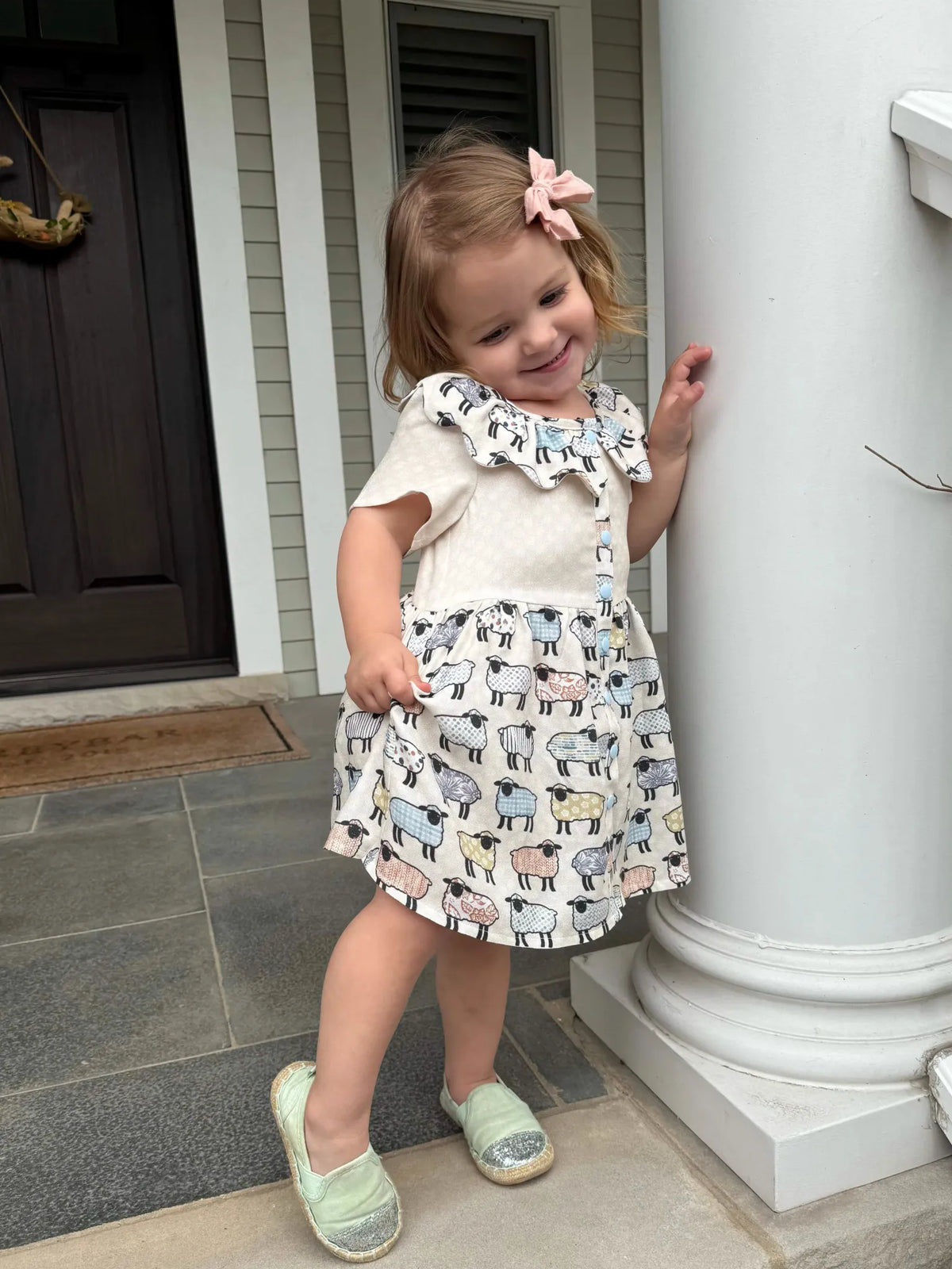 A young girl in a dress with a patchwork sheep pattern.