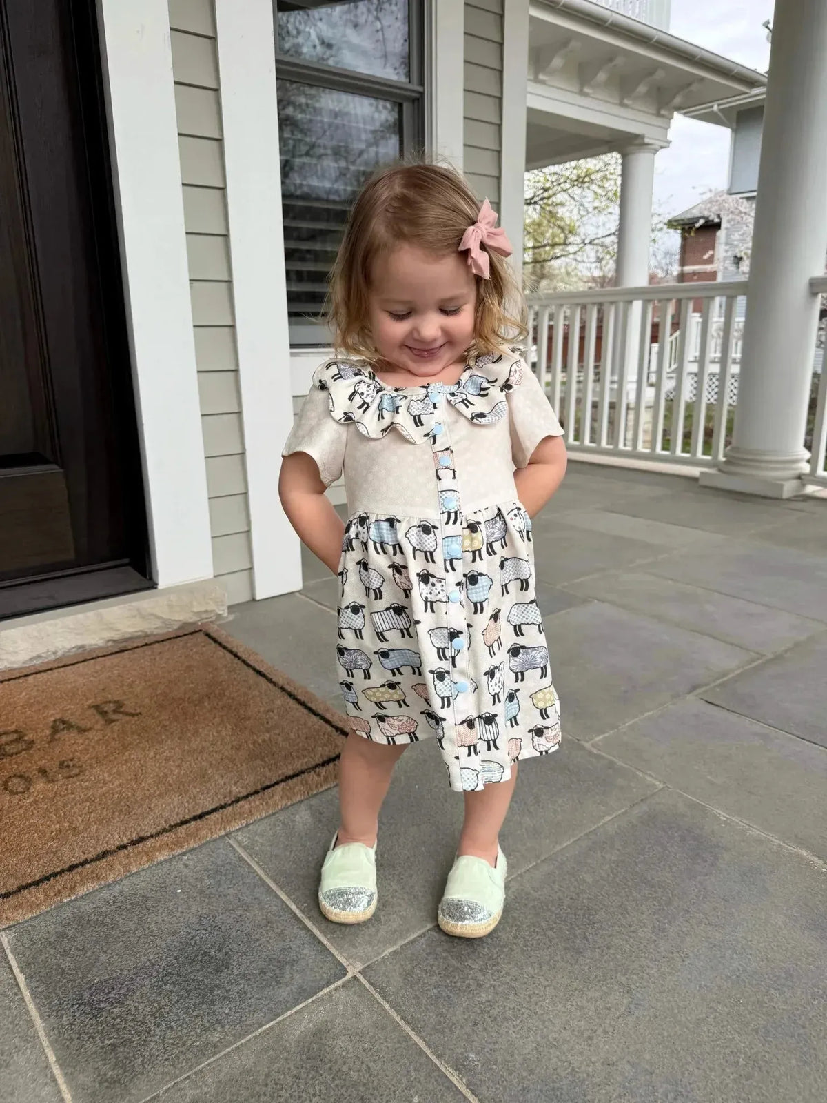 Patchwork sheep print craft fabric with white and gray sheep motifs on beige background.