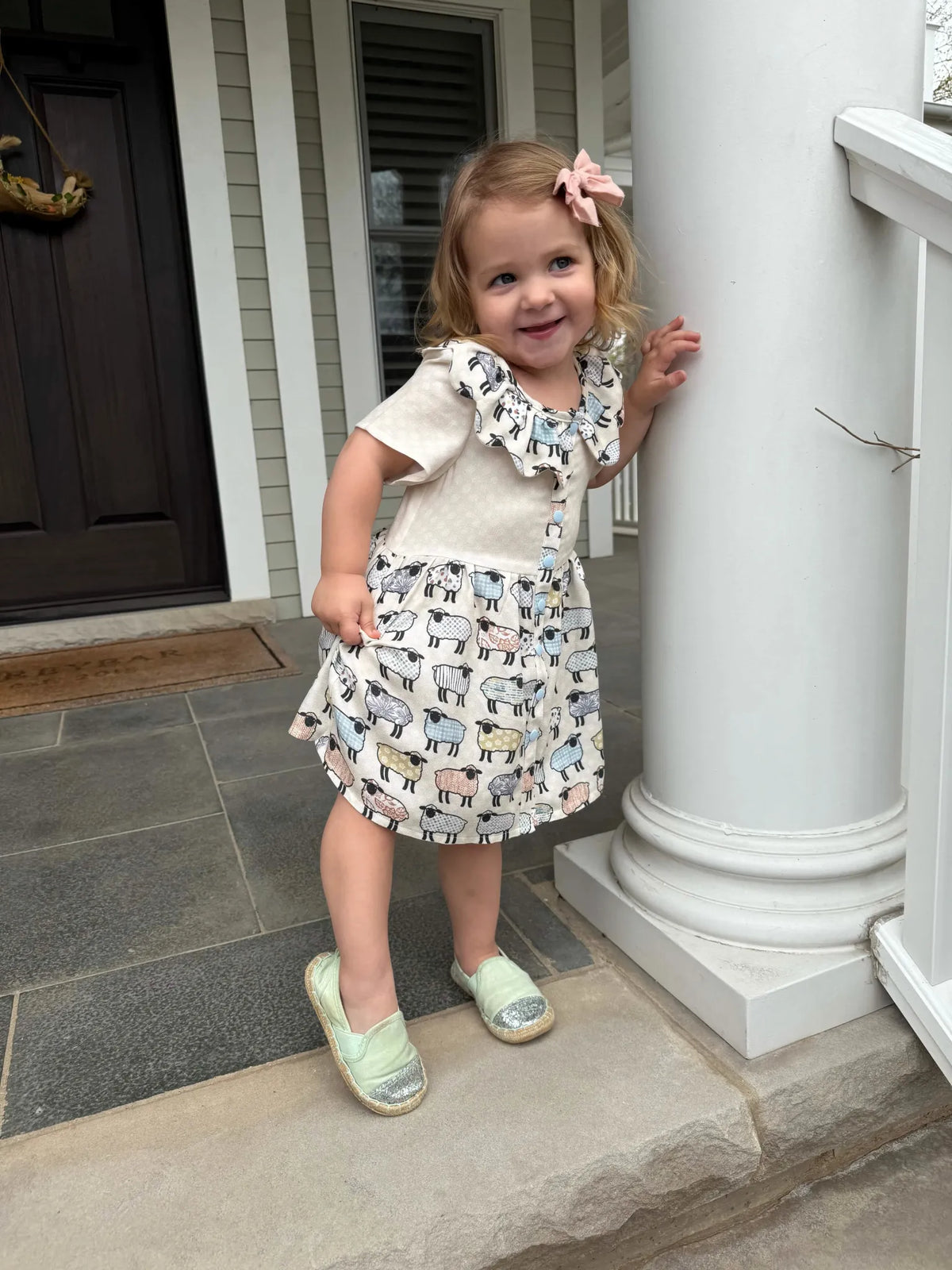 A young girl in a dress with a patchwork sheep pattern.