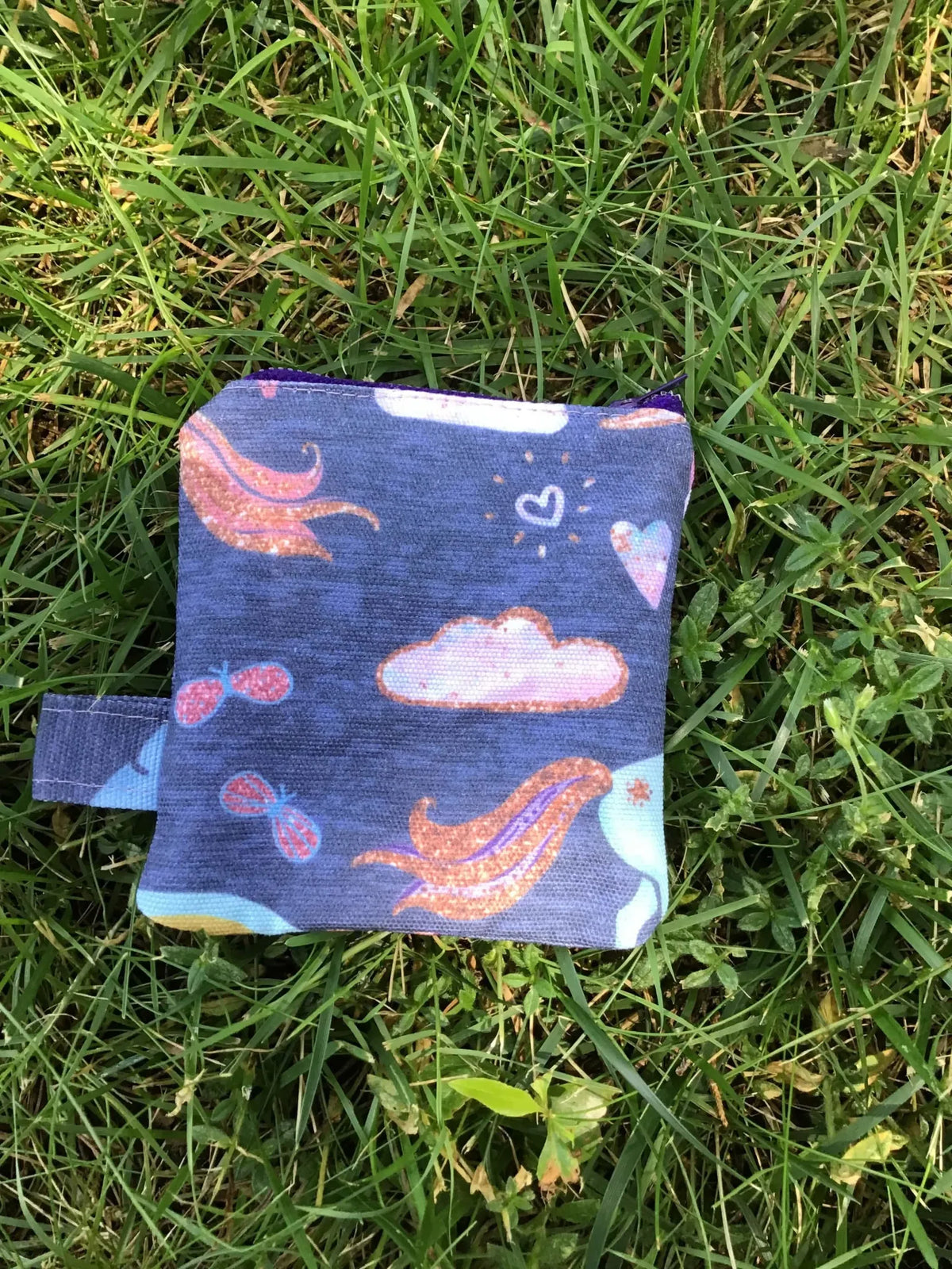 Navy unicorn fabric swatch with clouds and hearts on green grass.