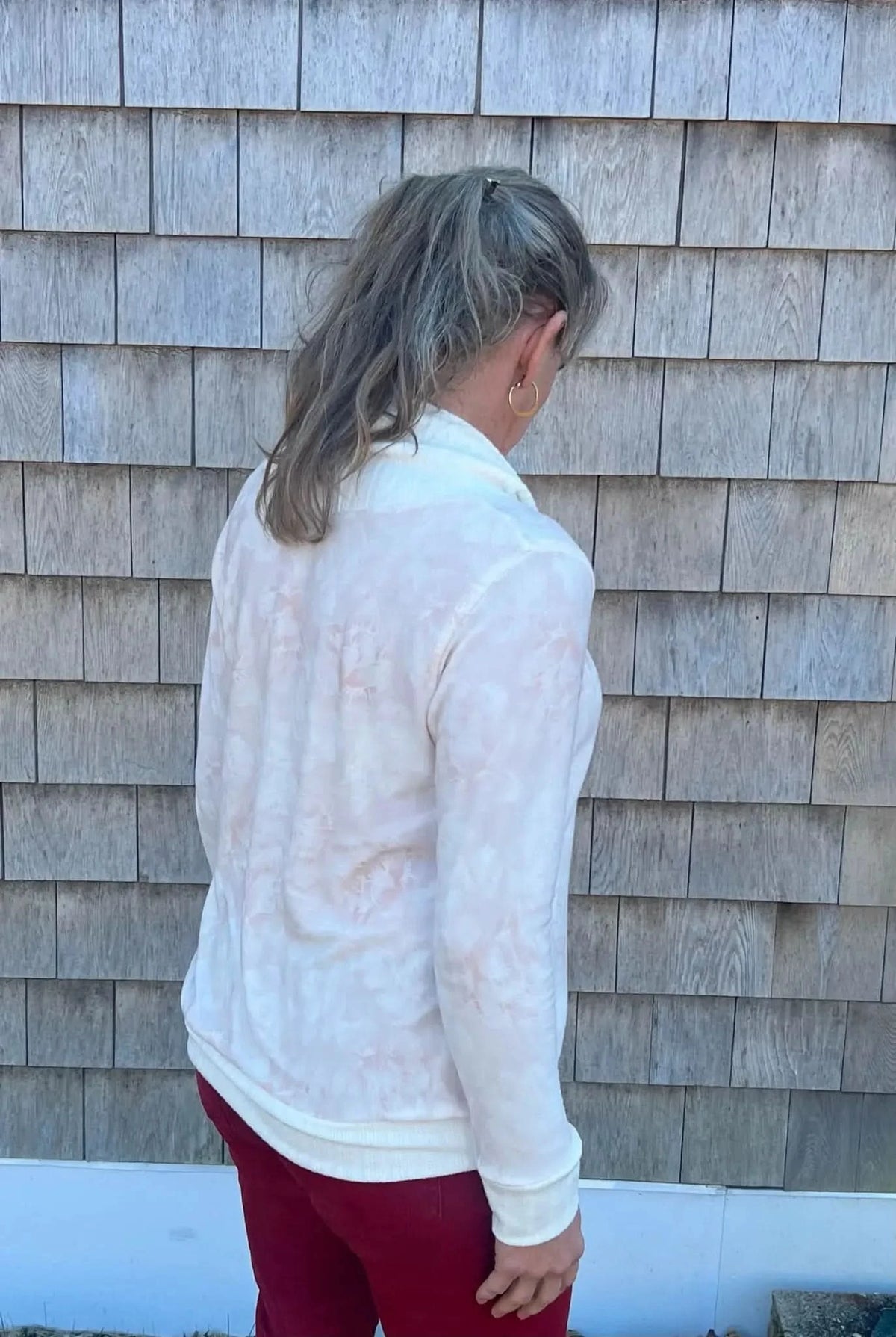A person from behind wearing a white top with a subtle pink floral pattern.