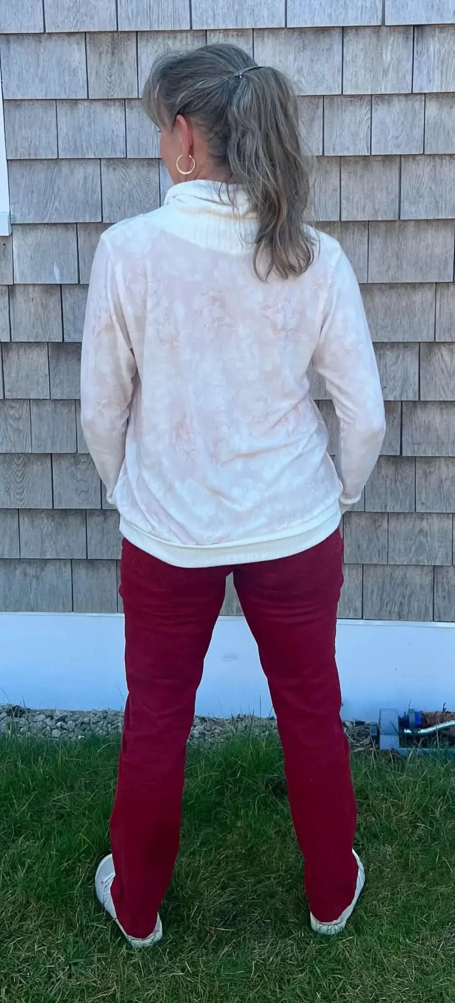 A person from behind wearing a light pink floral top and red pants.