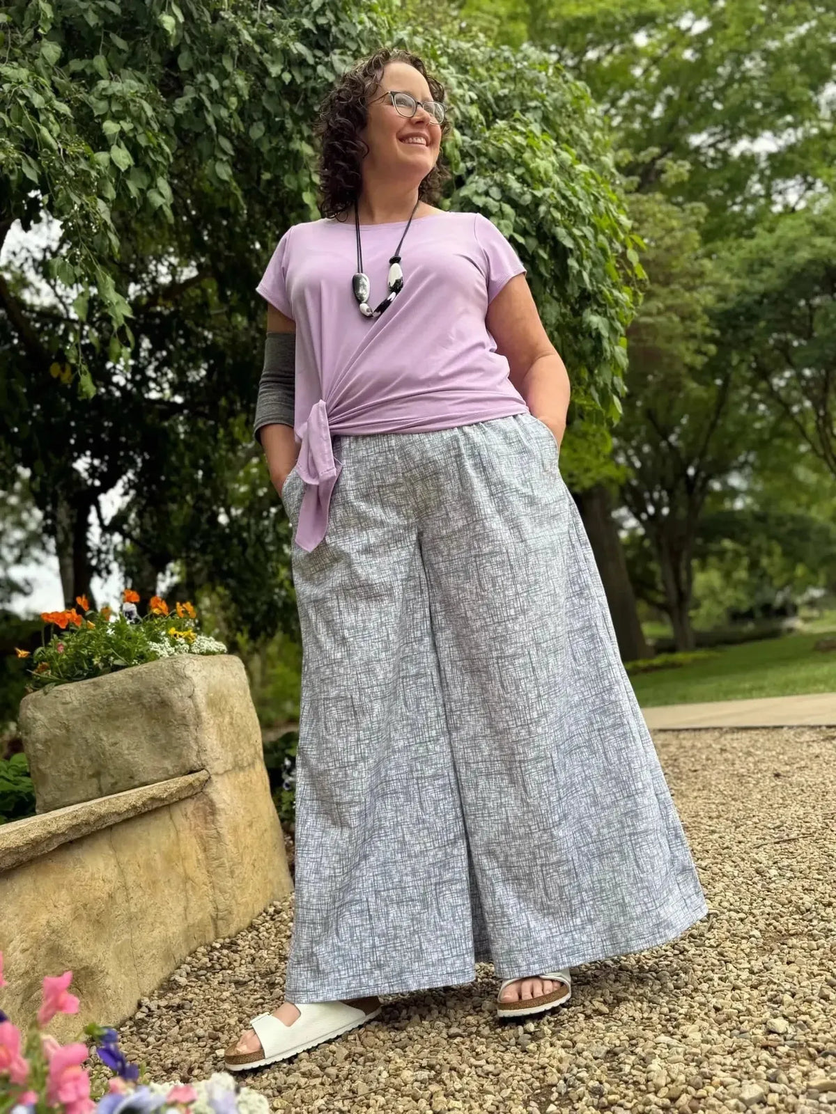 Woman modeling wide-leg pants in black hatch abstract print fabric outdoors.