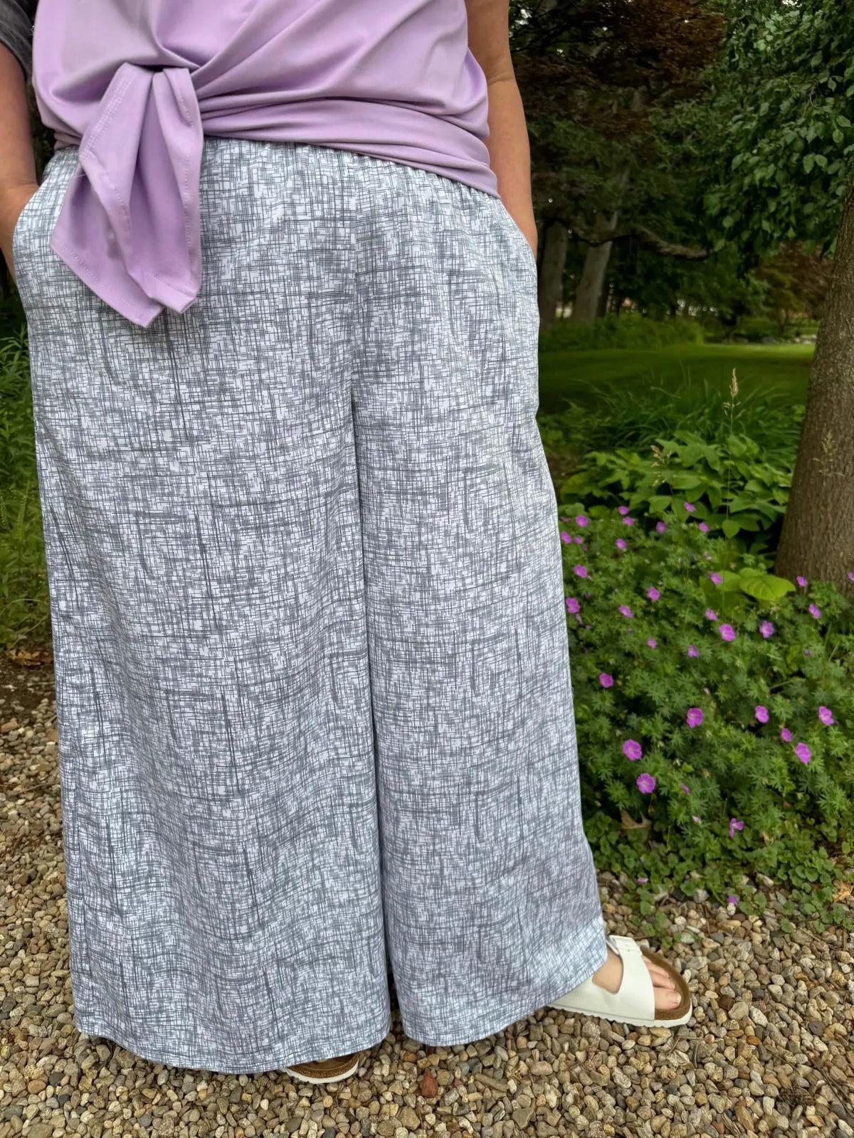 A person wears wide-leg pants in a black hatch pattern with a lavender top.