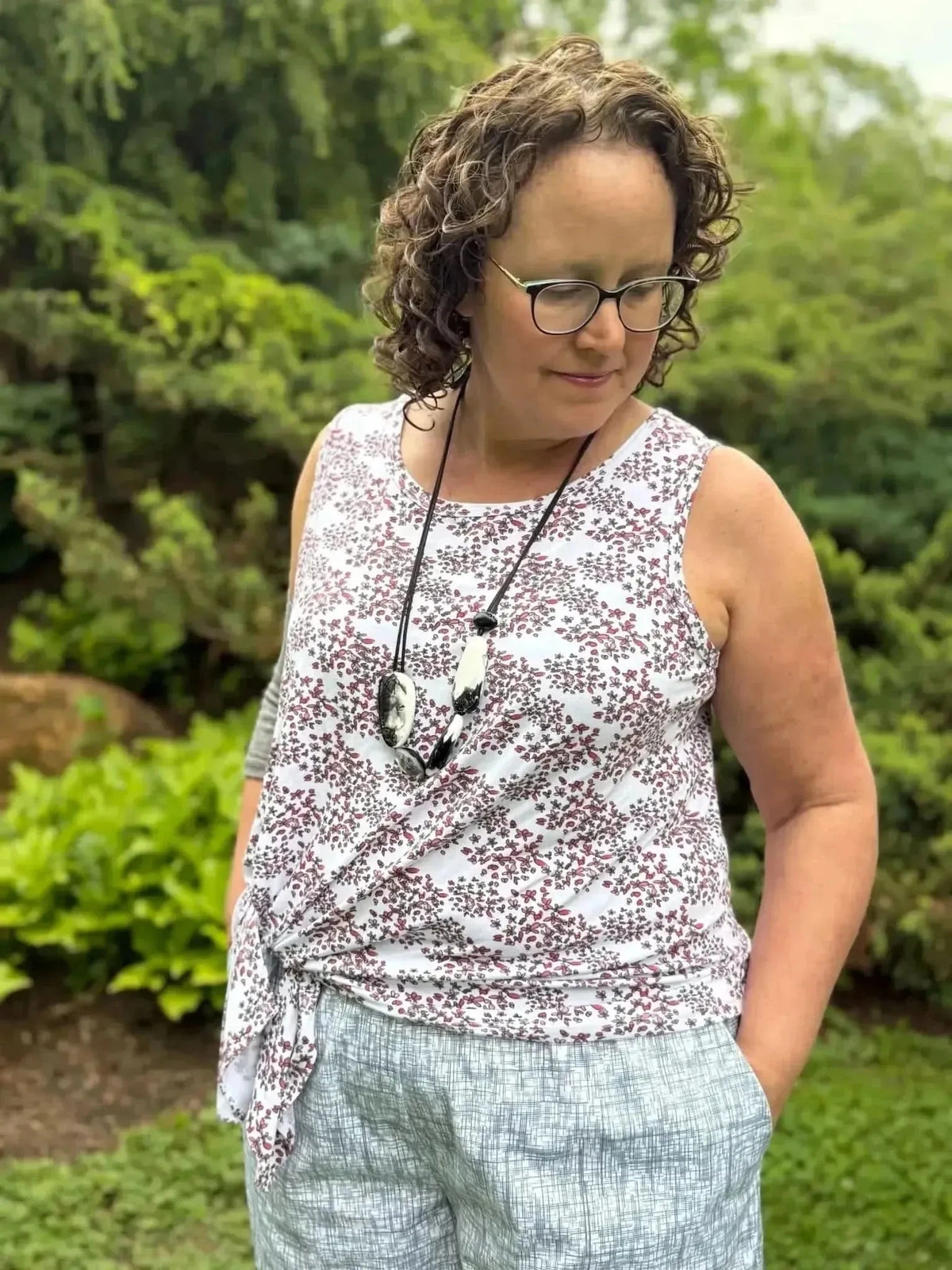 Woman modeling sleeveless red floral wrap top and gray shorts made from breathable fabric.