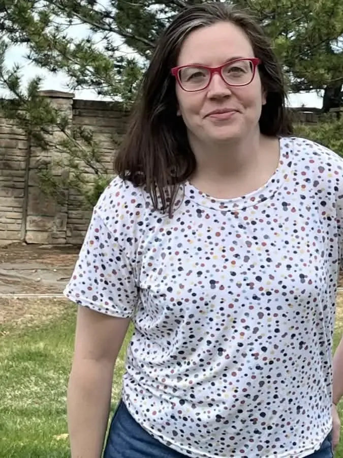 A woman wears a white t-shirt with a colorful sprinkles pattern.