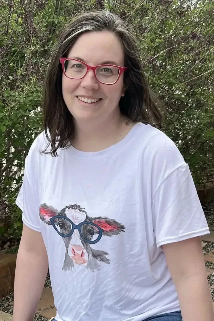 Woman modeling a white t-shirt with a cute cow print featuring red glasses.