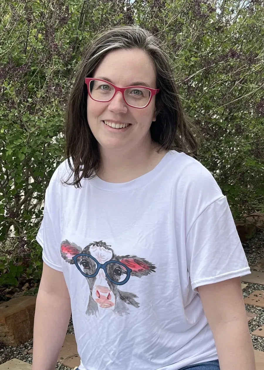 A woman wears a white t-shirt with a graphic of a calf wearing blue glasses.