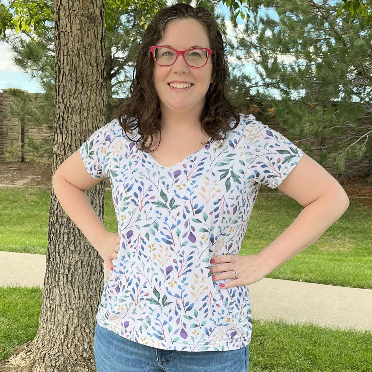 Woman wearing a patterned shirt standing outdoors near a tree
