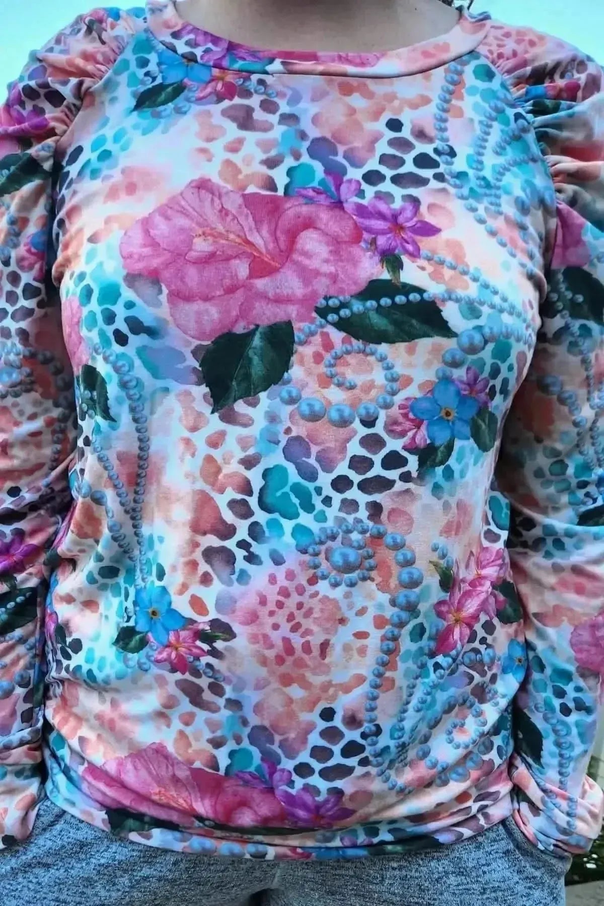 Vibrant tropical fabric with wild hibiscus flowers, pink blooms, green leaves, and blue accents on a textured background.