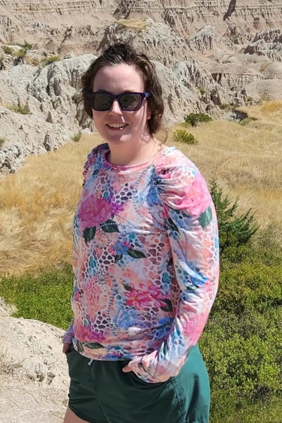 A woman wears a long-sleeved shirt with a vibrant floral and abstract pattern.