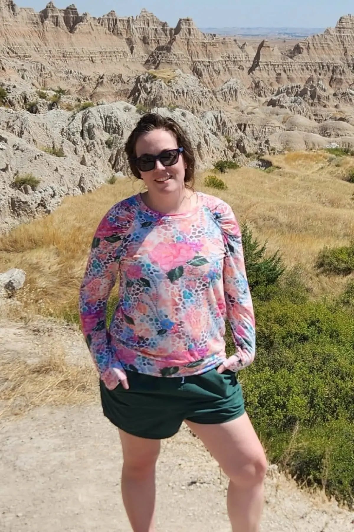 A woman wears a long-sleeved shirt with a vibrant floral and abstract pattern.