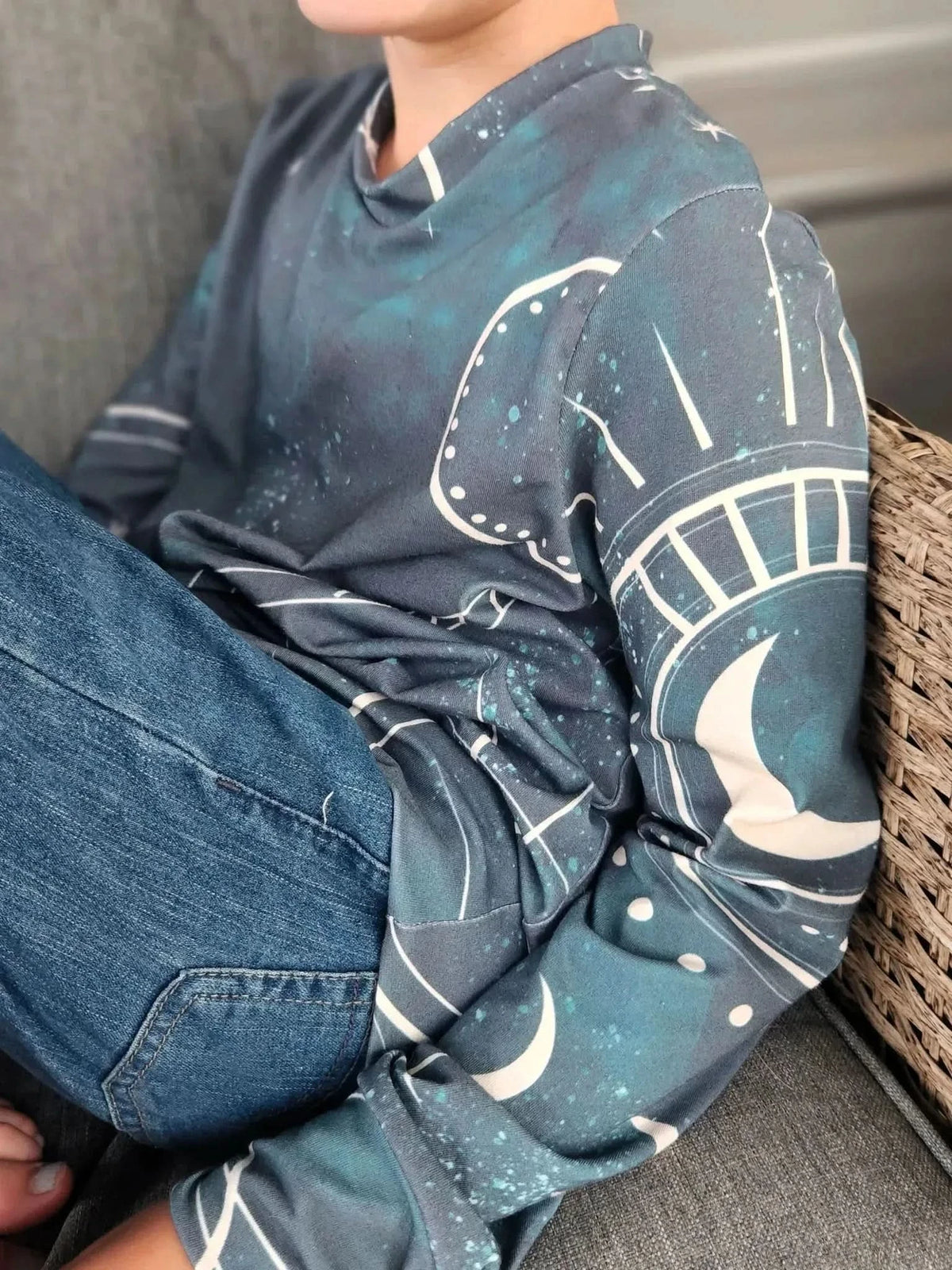 A person wears a long-sleeved shirt with a celestial sky pattern in green and blue.