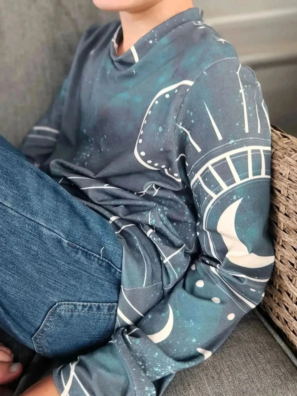 Green celestial sky fabric with fantasy print of moons, suns, and stars.