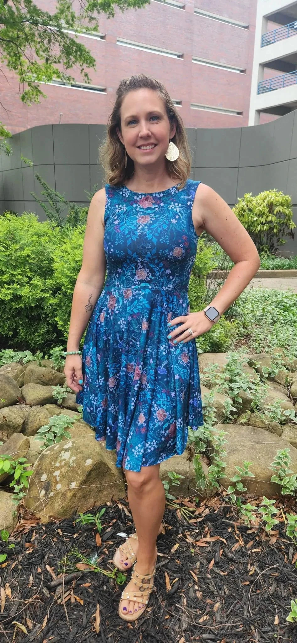 A woman wears a teal woodland print dress with floral patterns.