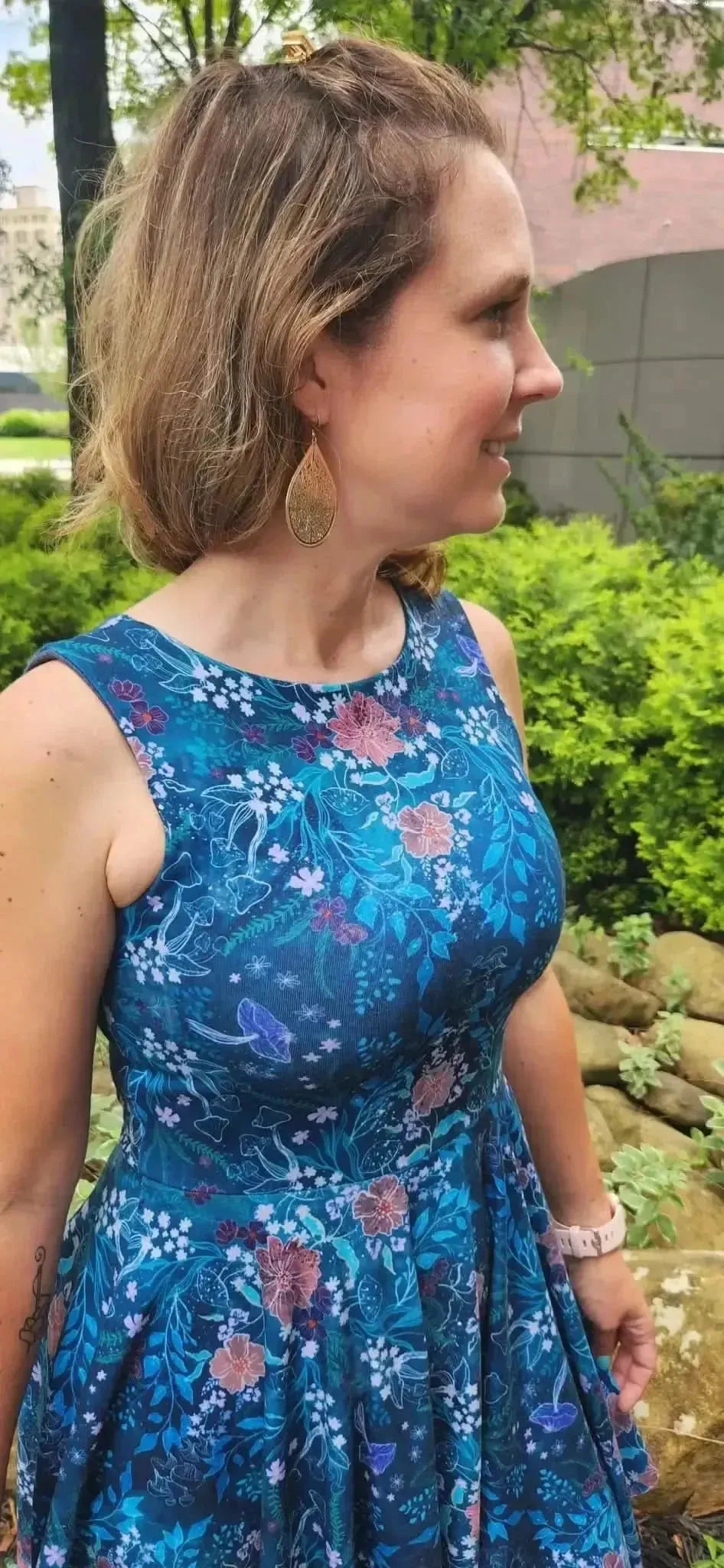 Teal woodland print fabric with floral patterns in a sewn dress.