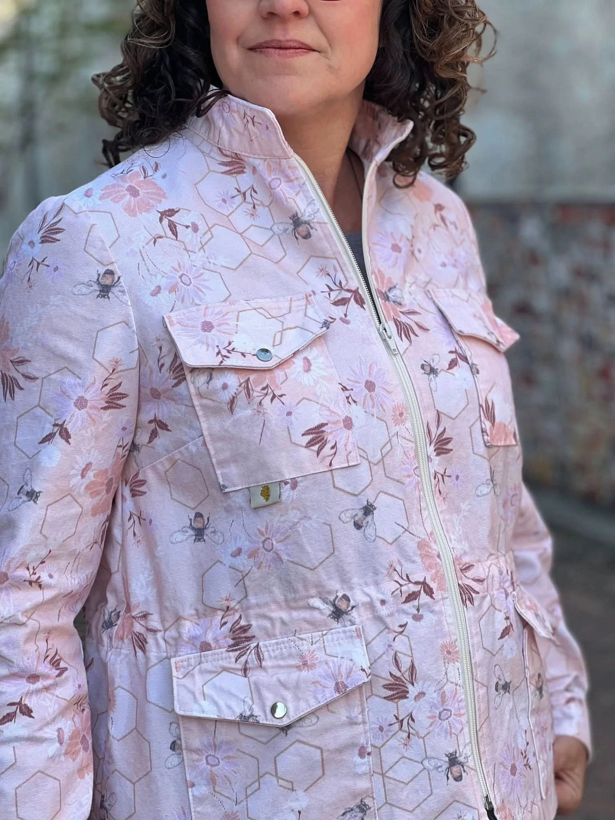 Woman wearing a peach jacket with a bee and floral pattern.