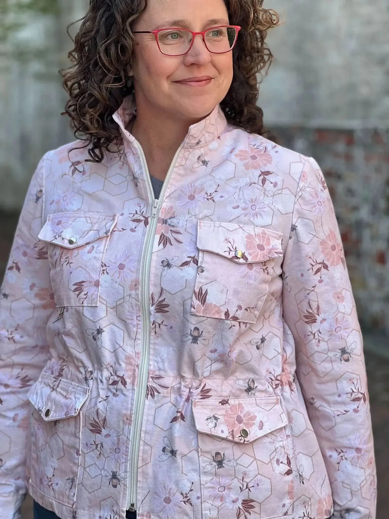 Woman wearing a peach jacket with a floral and bee pattern.