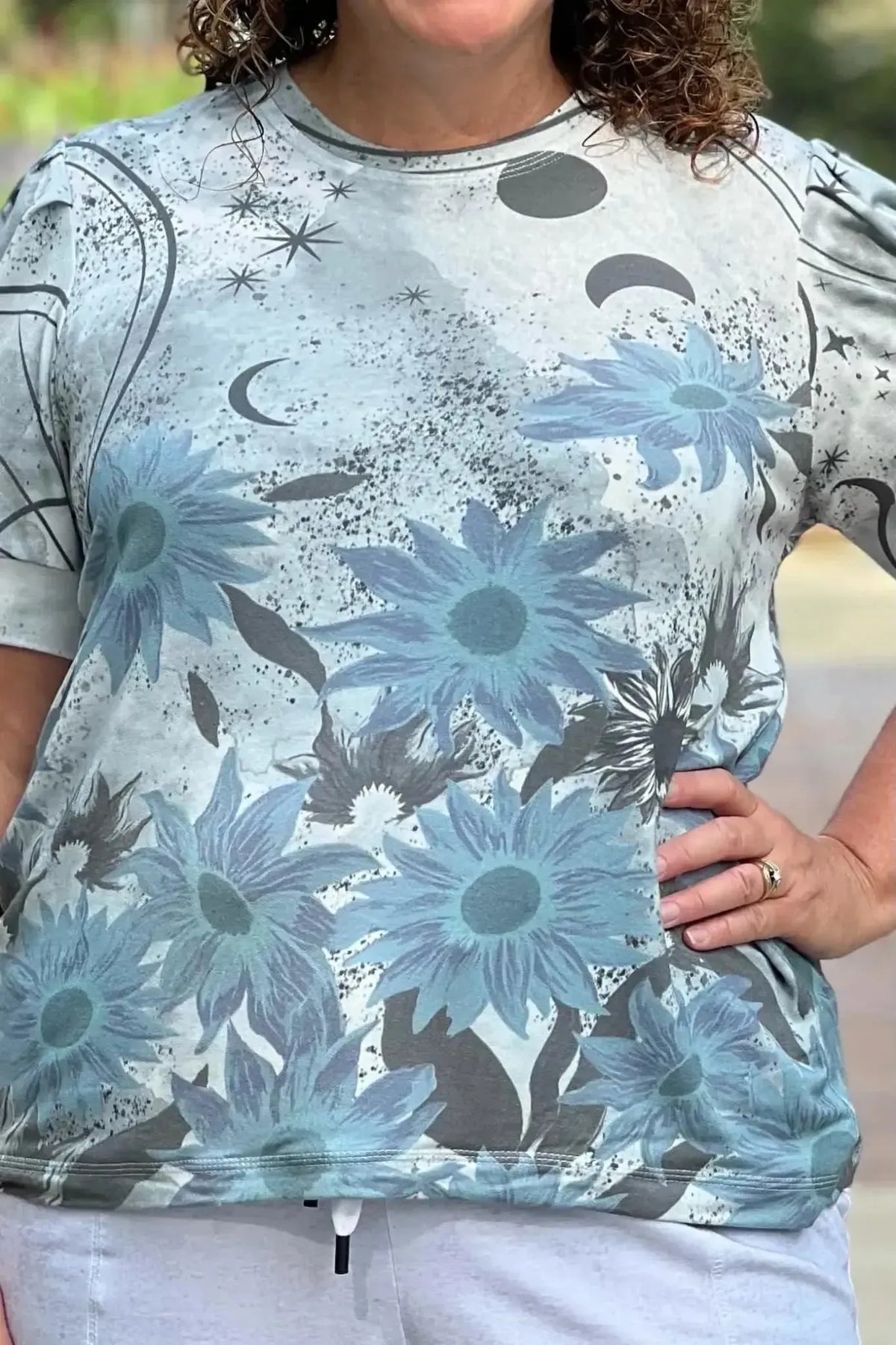 A woman wears a light blue shirt with a celestial sunflower pattern.