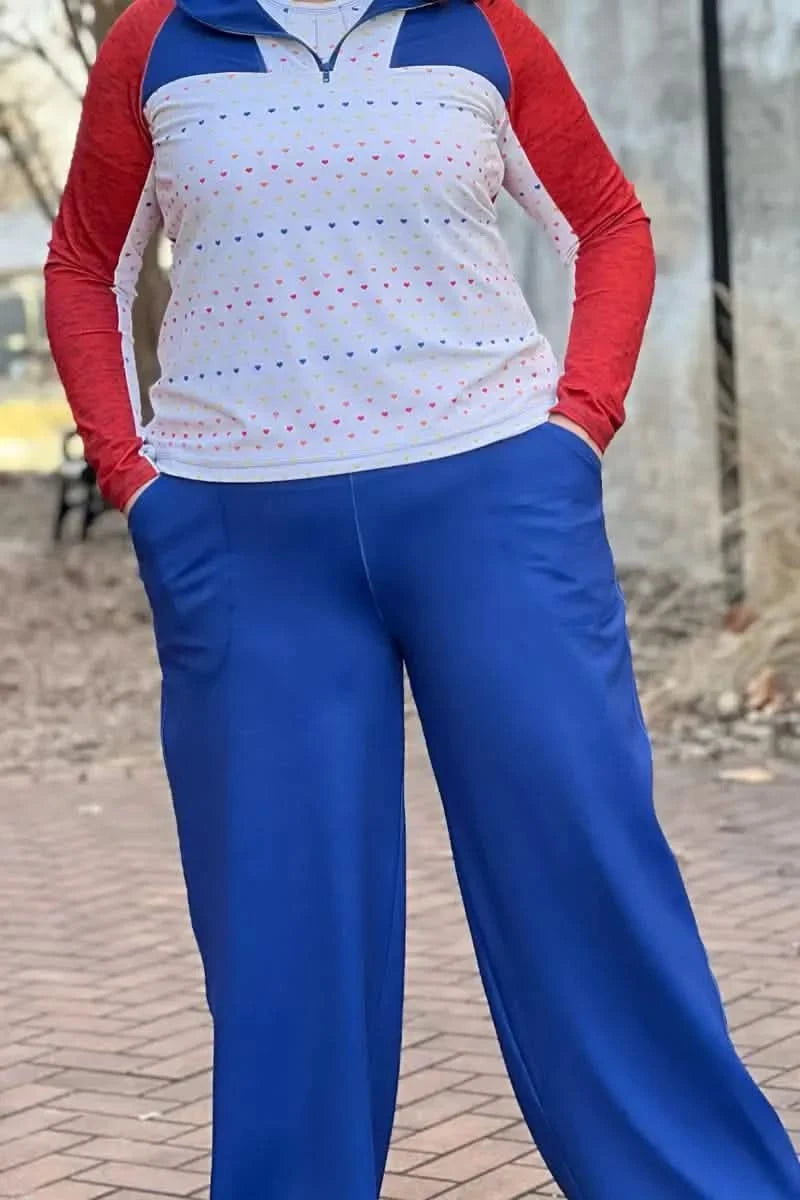 A person wearing a white shirt with colorful hearts and blue pants.