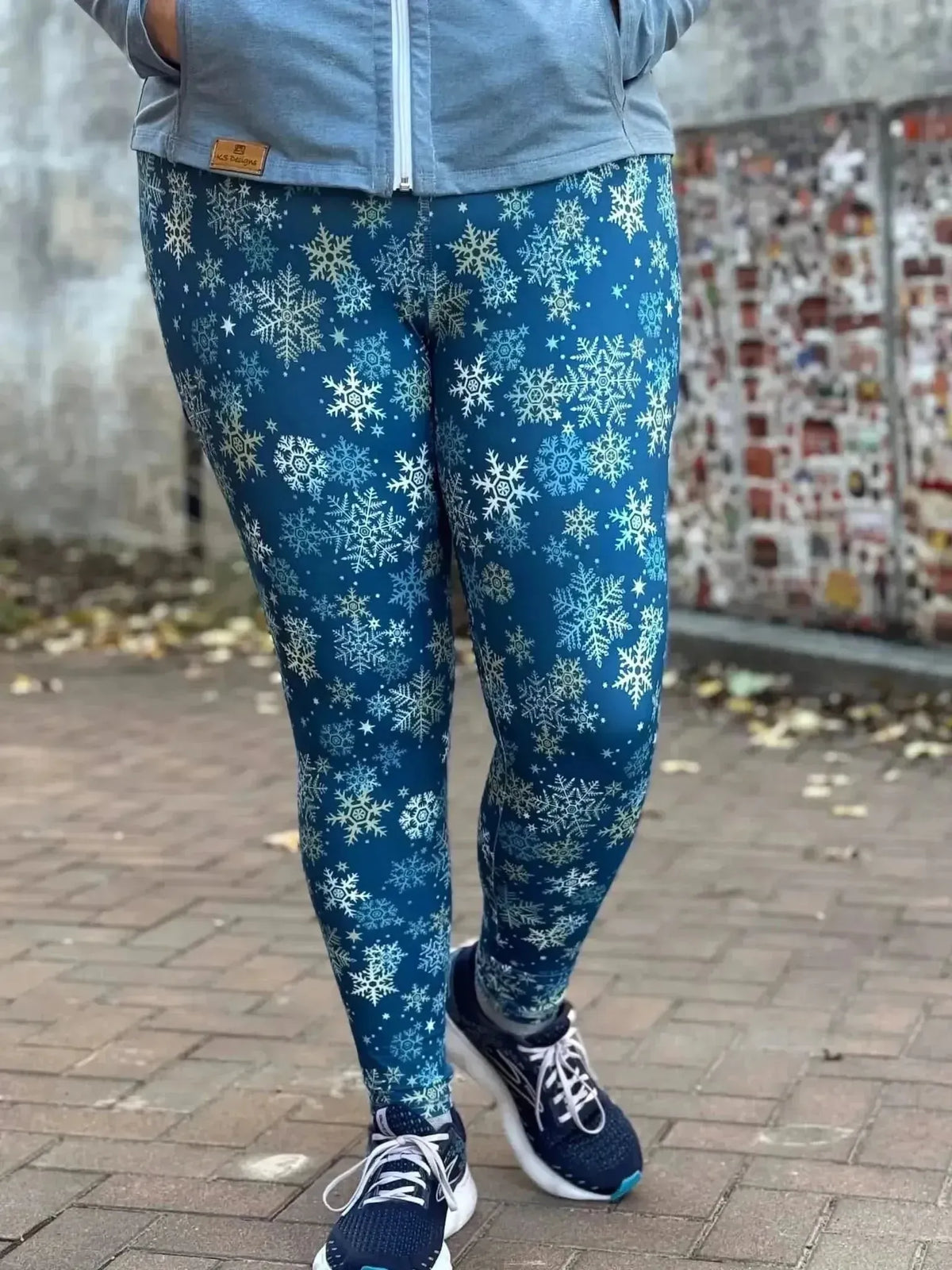 Blue leggings featuring a white snowflake print on navy fabric, modeled outdoors.