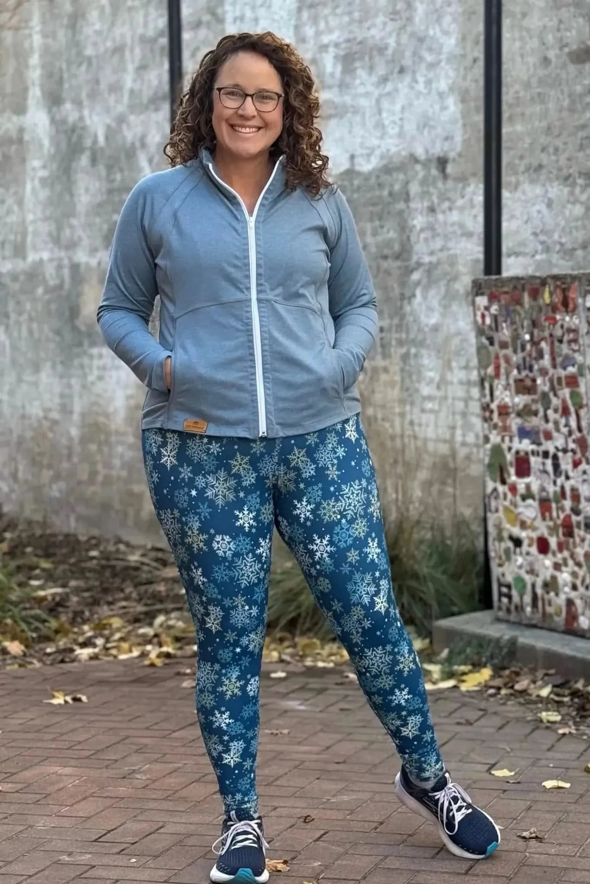 Woman wearing a light blue zip-up hoodie and leggings with a blue snowflake print.