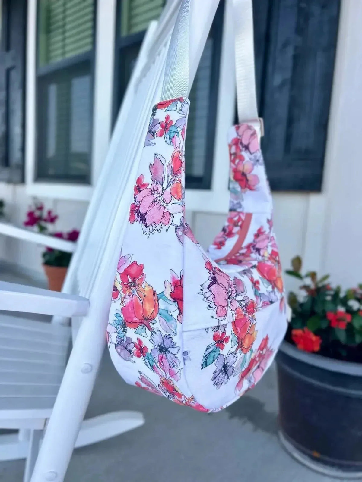White fabric with pink and purple floral Memory Garden pattern, draped over a white porch swing.