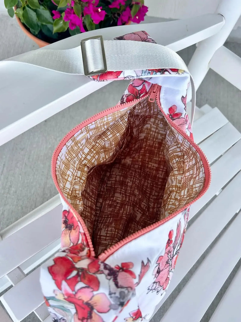 Open floral bag with a gold hatch pattern lining and a white adjustable strap.