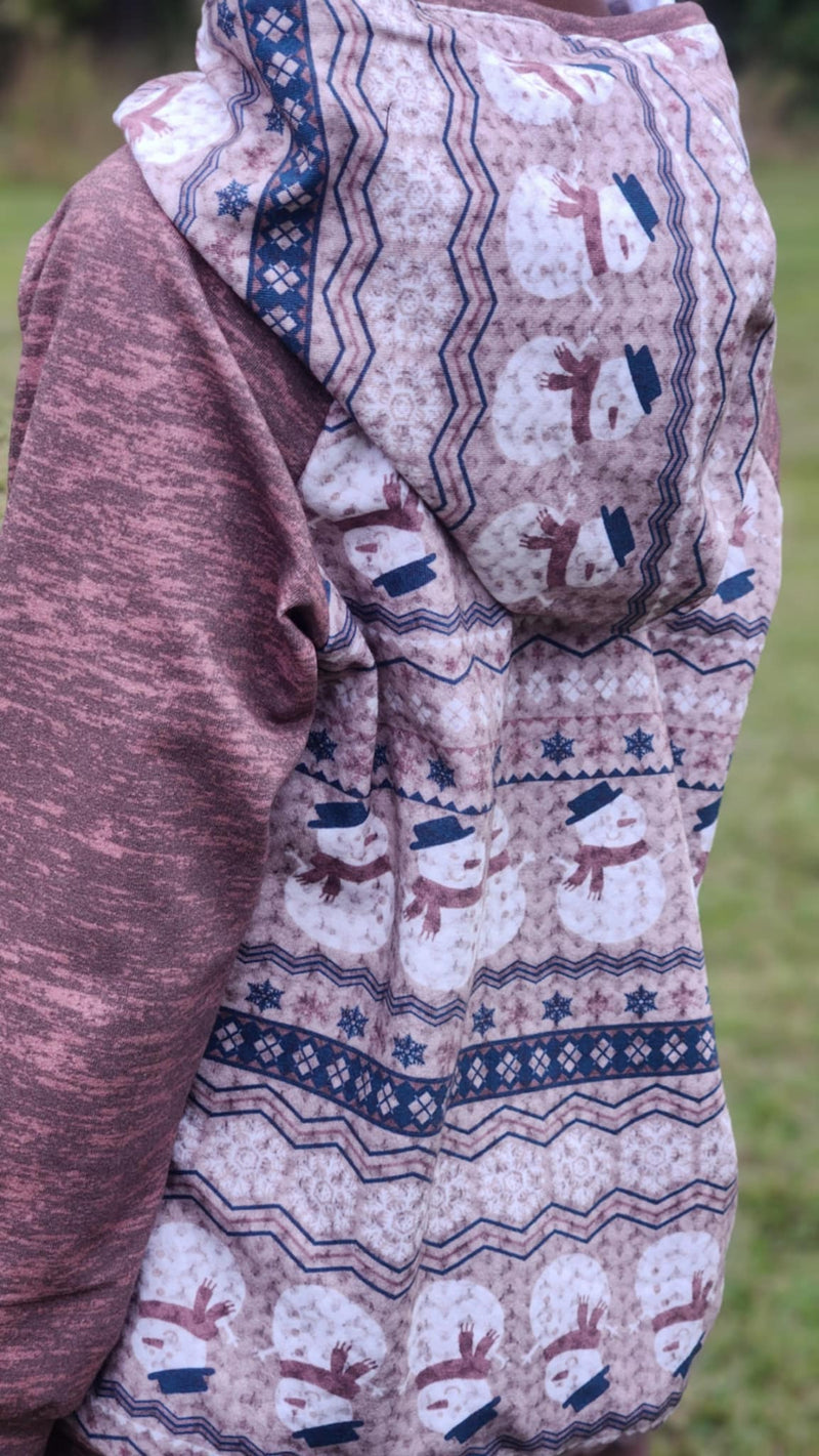A person wearing a hoodie with a snowman and snowflake pattern.