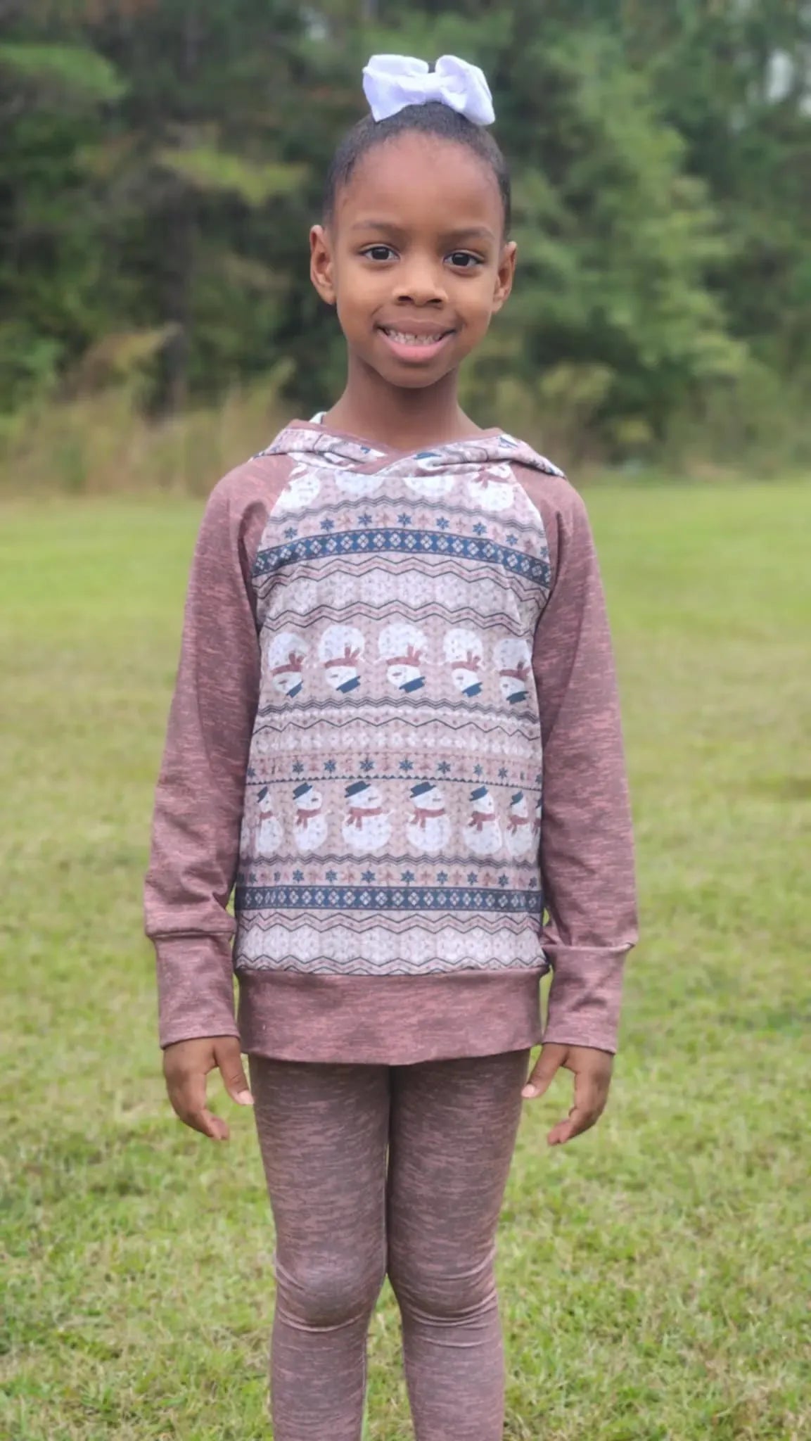A young girl wears a long-sleeved shirt and leggings with a snowman pattern.