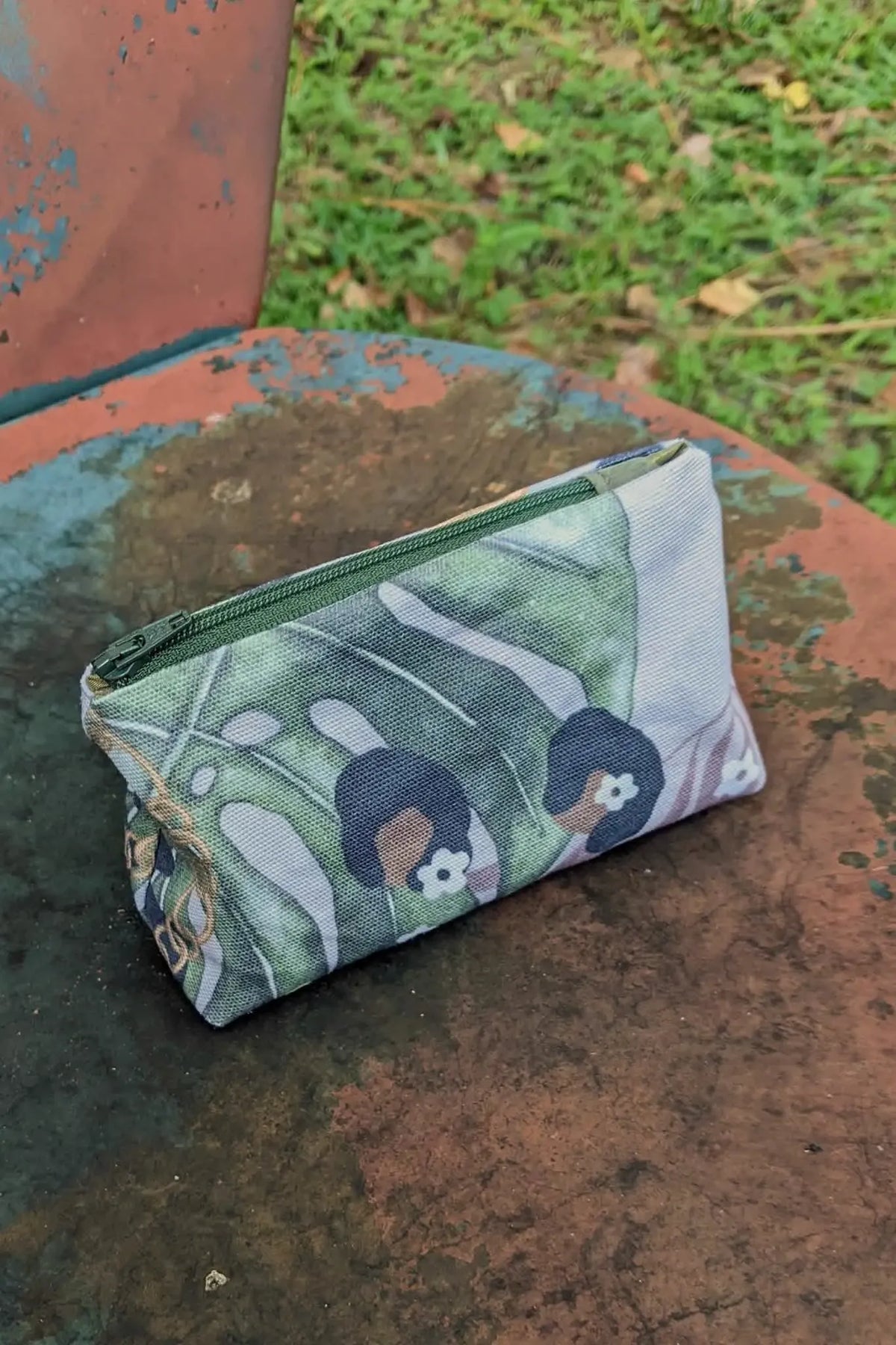 A small zippered pouch with a green, white, and black leopard print pattern.