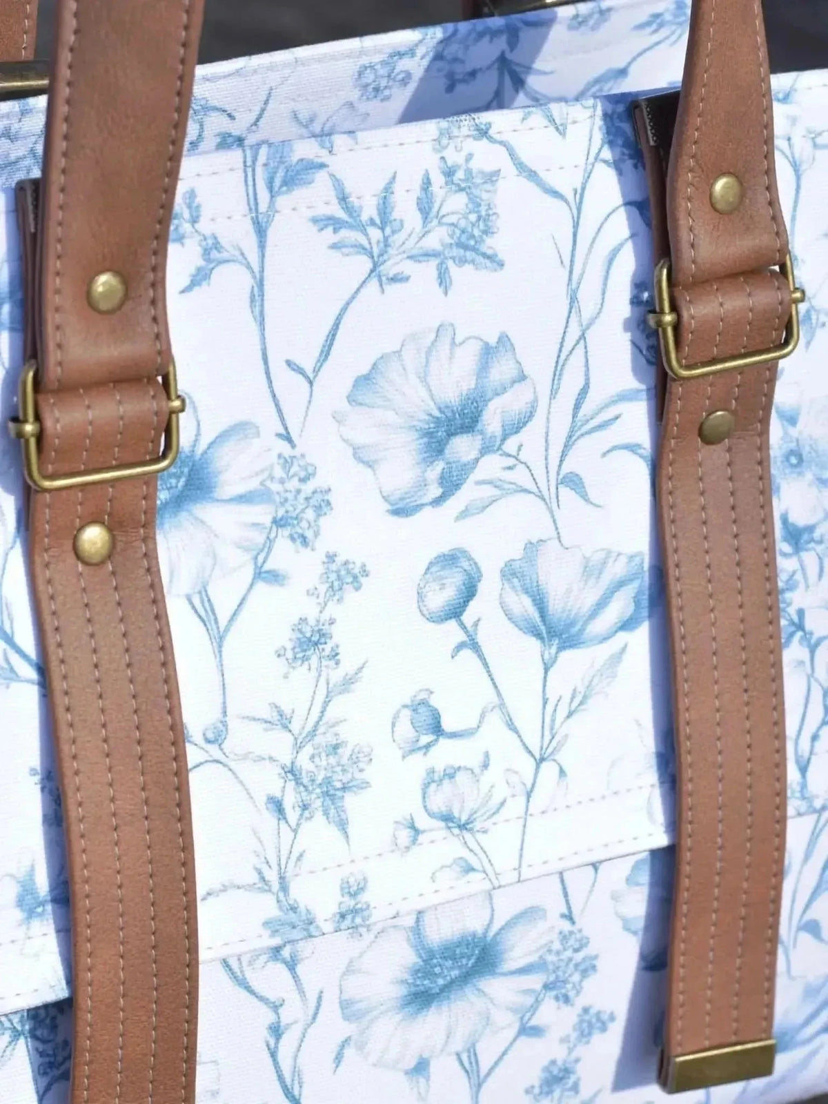 Blue botanical print fabric with garden flowers and leaves on white background.