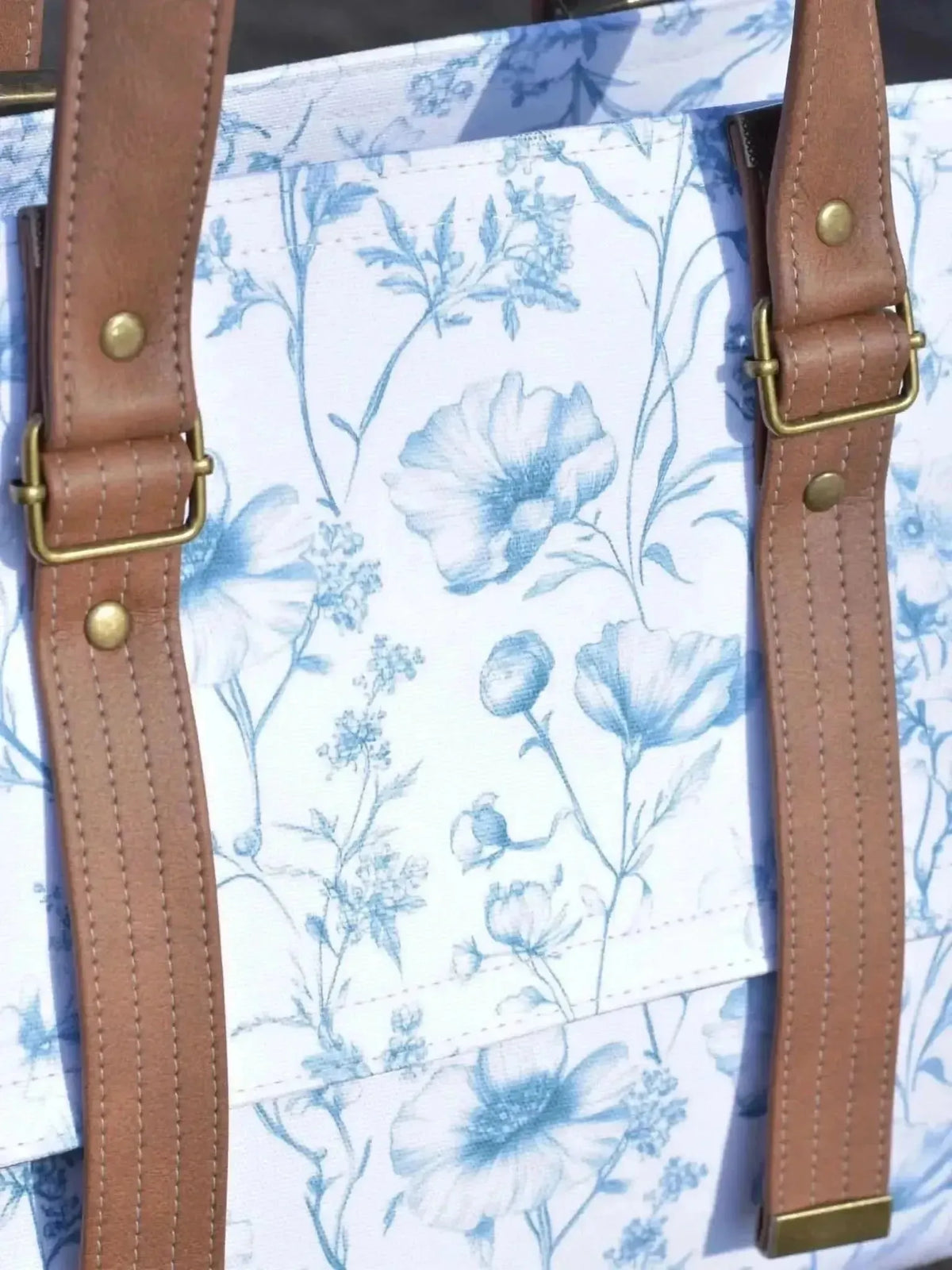 Blue botanical print fabric with garden flowers and leaves on white background.