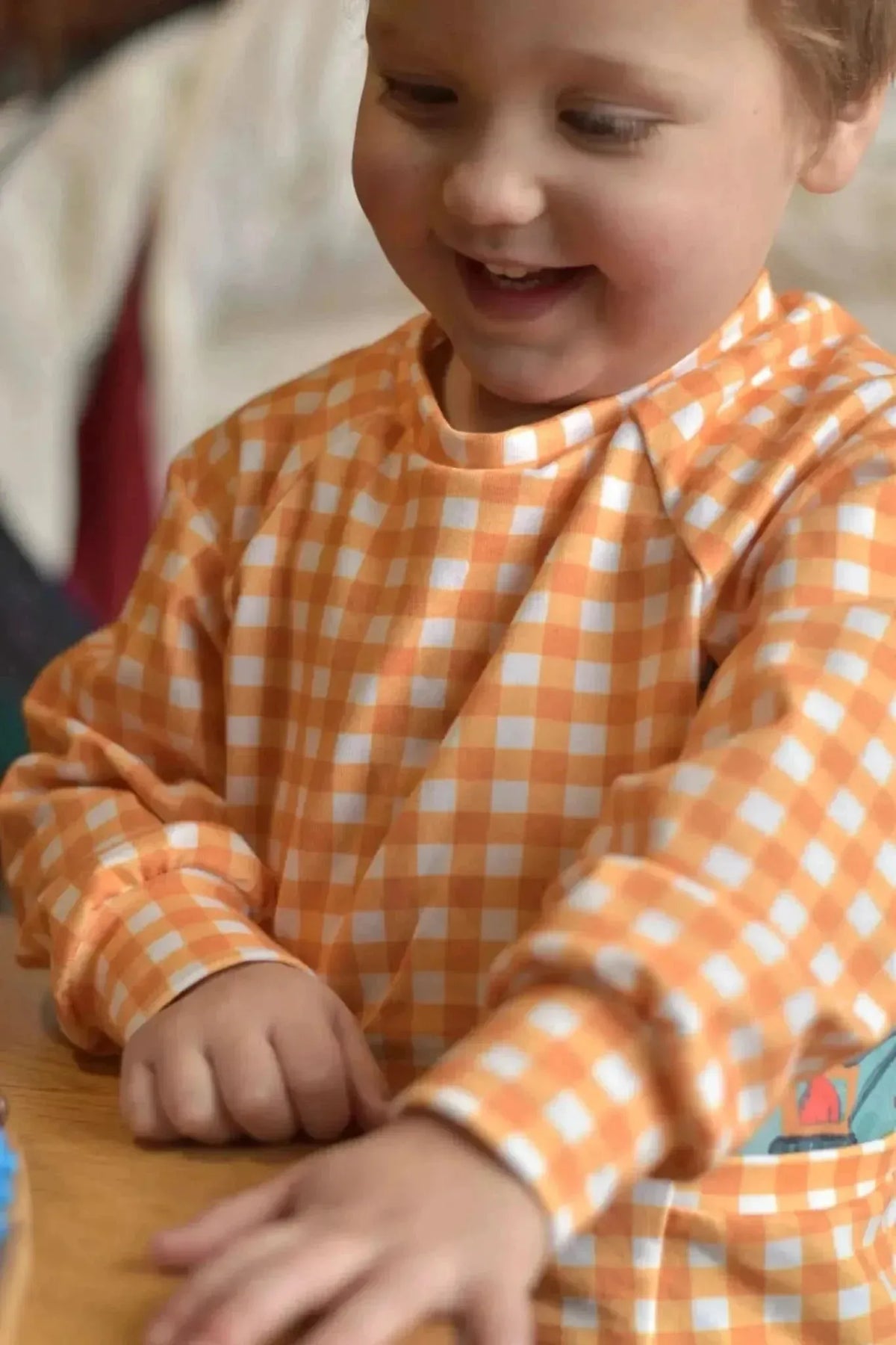 A child wears a long-sleeved shirt made from mustard gingham fabric.