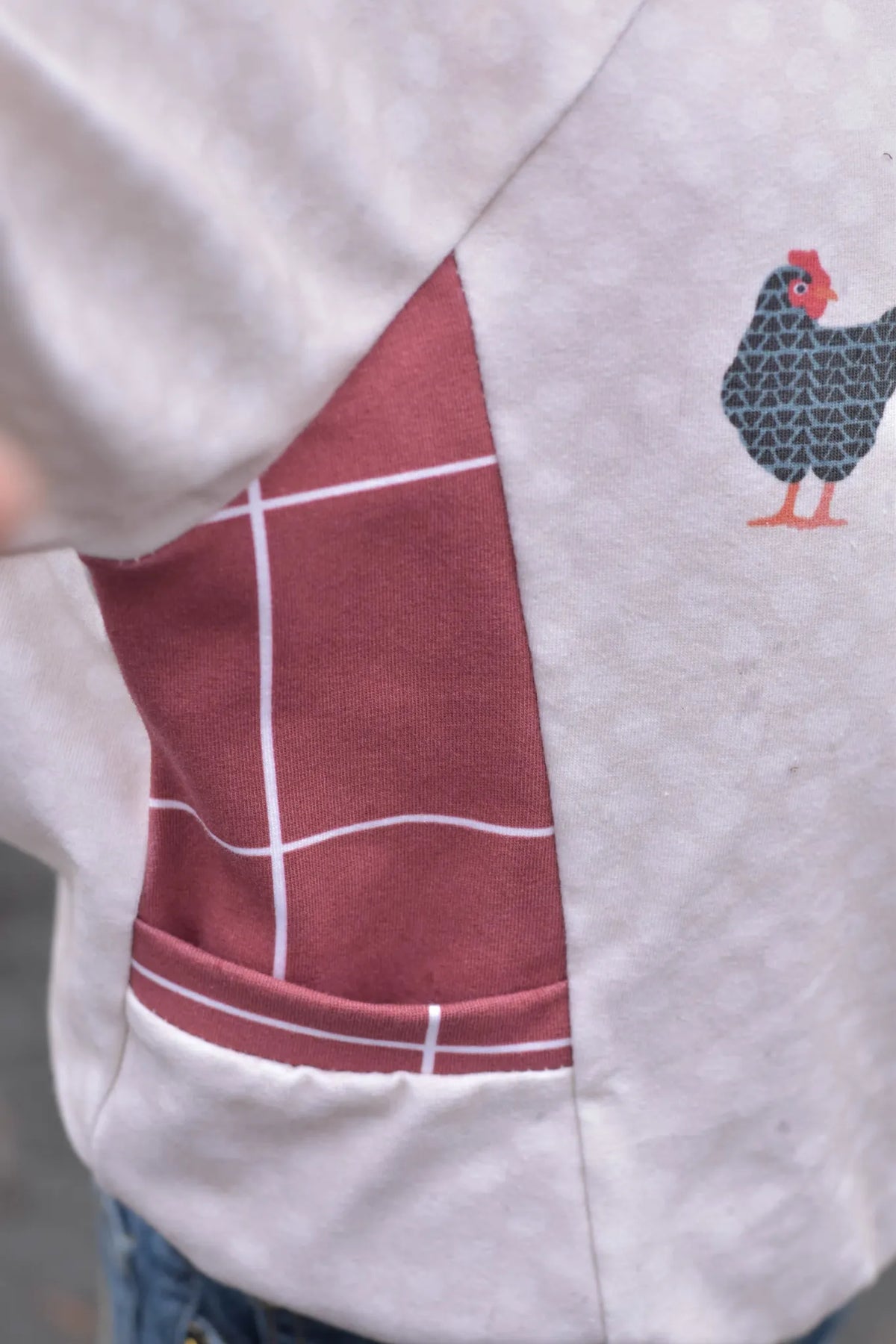 A close-up of a garment featuring a red windowpane pattern and a chicken graphic.