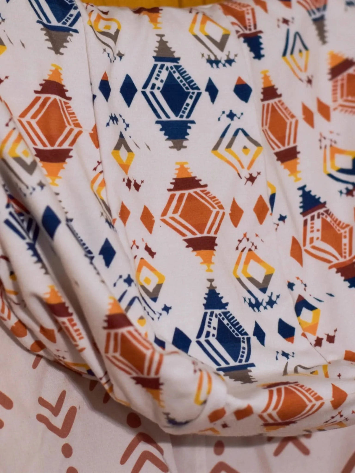 Fabric with a desert diamond pattern in orange, blue, and brown.