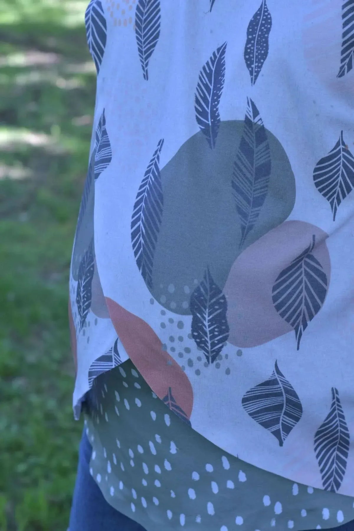 Fabric with a white background and a pattern of leaves and abstract shapes.